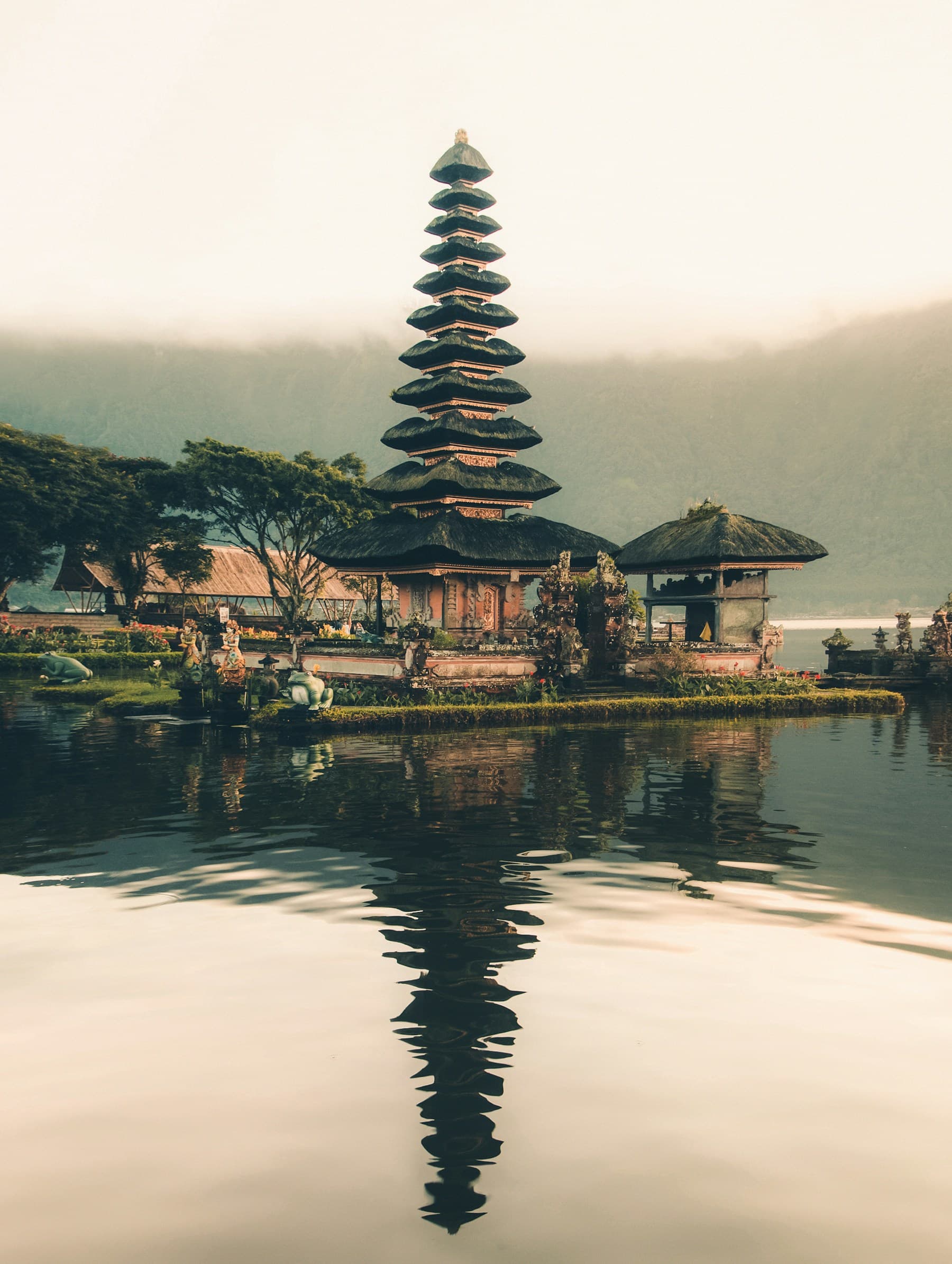 A Balinese temple reflected in a tranquil lake, surrounded by tropical greenery